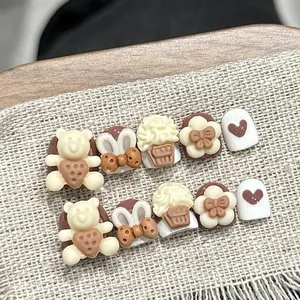 Detail von 3D-Bären und Cupcake-Mustern auf handgefertigten braun-cremefarbenen Nägeln