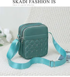 Détail du sac bandoulière en nylon sarcelle avec broderie flocon de neige et multiples zips