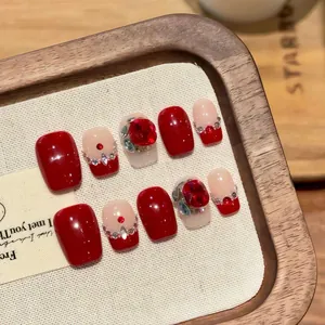 Detailed close-up of handmade red cat-eye press-on nails with luxury rhinestones and pearls