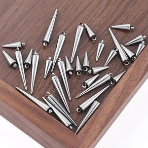 Detailed view of silver stainless steel spiked cone pendants on a rustic wooden tray