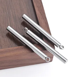 Gepolijste roestvrijstalen cilinderhangers voor DIY-sieraden gepresenteerd op hout