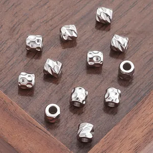 Zylindrische Edelstahlperlen mit Textur für DIY-Schmuck auf dunklem Holzhintergrund
