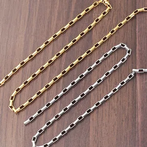 Detailed view of gold and silver rectangle link chains on a textured wooden background