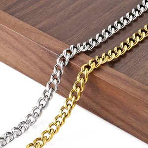 Polished stainless steel Cuban link chains in gold and silver finish on a wooden tray