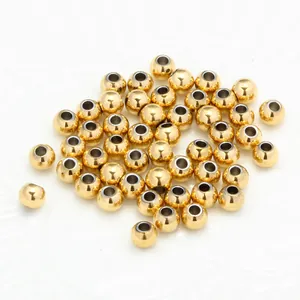 Vista macro de cuentas espaciadoras redondas de acero dorado con agujeros para joyería DIY