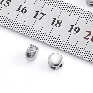 Close-up of polished stainless steel stopper beads next to a ruler for size reference