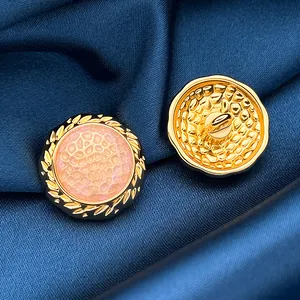 Macro shot of gold leaf-bordered metal buttons with pink enamel centers on silk