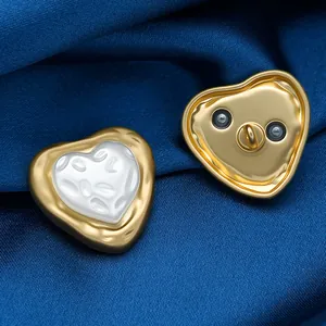 Detailed macro view of heart-shaped gold-rimmed pearl buttons on dark blue satin fabric
