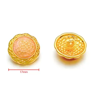 Detail of 17mm gold metal button with pink honeycomb texture and leaf relief border