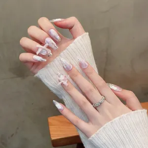 Macro view of coffin nails featuring 3D pink ribbon bows and delicate marble patterns