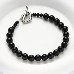Close-up of a gradient black faux pearl bracelet featuring a silver metal OT toggle clasp