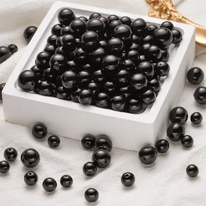 Close-up of assorted glossy black ABS faux pearls with pre-drilled holes for DIY jewelry