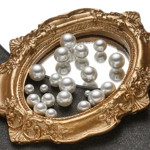 Macro shot of white high-gloss ABS faux pearls in various sizes inside a vintage gold frame