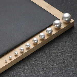Polished white ABS pearls in various sizes arranged diagonally on a textured background