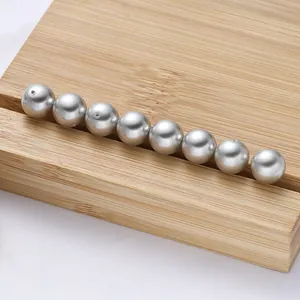 Dettaglio di perle di vetro grigio argento con foro passante su supporto in legno