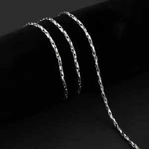 Détail d'une chaîne en acier inoxydable poli enroulée sur un support de présentation noir