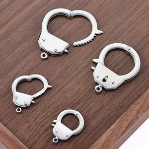 Stainless steel handcuff-shaped charms for DIY jewelry making on wood background