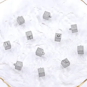 Detailopname van zilveren kubusvormige hangers voor DIY-sieraden in een wit schaaltje