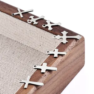 Verschiedene Edelstahl Kreuzanhänger für DIY-Schmuck auf einem Holztablett präsentiert
