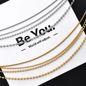 Gold- und silberfarbene Edelstahl-Kugelketten und Boxketten auf minimalistischer Karte