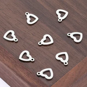 Polished stainless steel heart pendants for DIY jewelry on a dark wooden tray