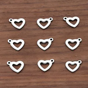 Polished stainless steel hollow heart pendants arranged on a dark wood background for DIY