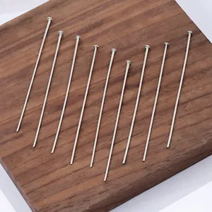 Close-up of ten silver stainless steel T-head pins on a walnut wood texture base