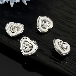 Macro shot of silver metal heart-shaped buttons with rhinestones and white inlay details