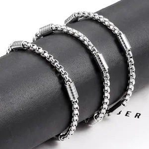 Silver stainless steel box chain bracelet with textured accents on a black display roll