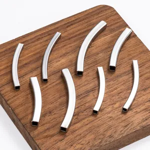 Set of eight curved square stainless steel spacer beads for DIY jewelry on wood base
