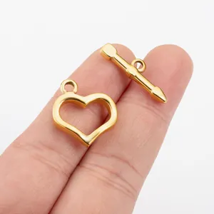 Gros plan d'un fermoir à bascule cœur en acier doré tenu par la main pour bijoux