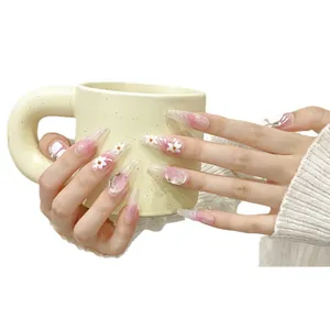 Handmade pink gradient press-on nails with white floral patterns and gold foil accents