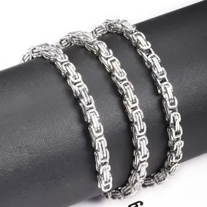 Close-up of silver Byzantine stainless steel chain on a black cylindrical jewelry stand