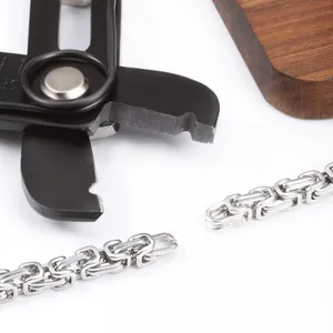 Close-up of a black precision wire cutter cutting through a stainless steel Byzantine chain