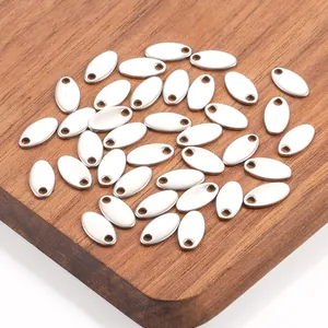 Polished stainless steel oval charms for DIY jewelry making displayed on a wood surface