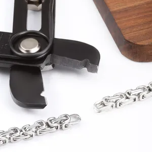 Polished silver Byzantine chain with black jewelry pliers on white and wood backdrop