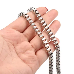 Minimalist silver stainless steel box chain necklace held by hand on white background