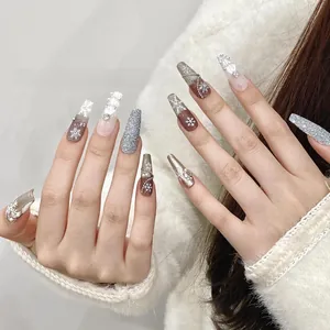 Détail de faux ongles de Noël forme cercueil avec flocons de neige, perles et paillettes