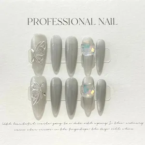 Detailed macro of dark grey cat-eye press-on nails with white butterfly and crystal accents