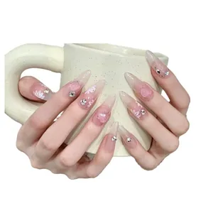 Handmade almond press-on nails with pink gradient, white flowers, and 3D heart gems