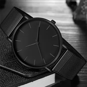 Minimalist all-black quartz watch with mesh strap on textured leather surface