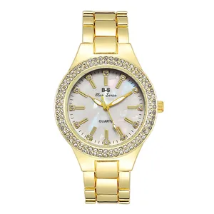 Macro detail of gold luxury watch with rhinestone bezel and mother of pearl dial
