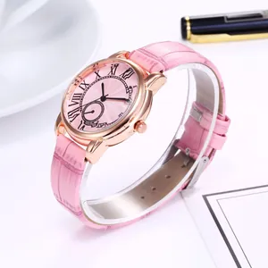 Detail of pink leather watch strap with roman numerals and rose gold case on white desk
