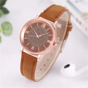 Detail of rose gold quartz watch with starry dial, roman numerals and brown leather strap