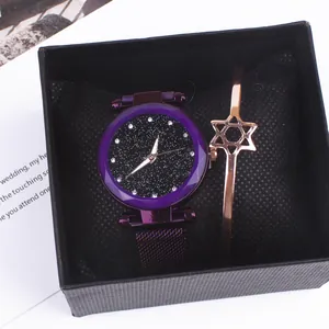 Detail of star dial watch and rose gold star bracelet set in a black textured gift box