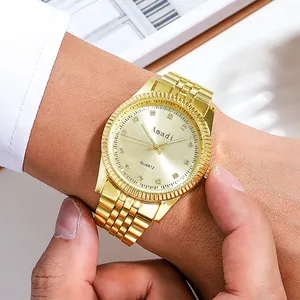 Gros plan d'une montre à quartz dorée avec index en strass et lunette cannelée au poignet