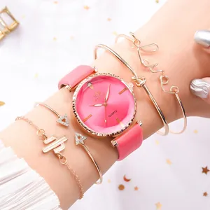 Détail de la montre à quartz en PU rose avec quatre bracelets dorés à la mode sur le poignet