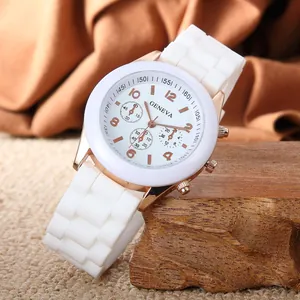 Detail of white silicone strap and rose gold Geneva watch on a dark wood block