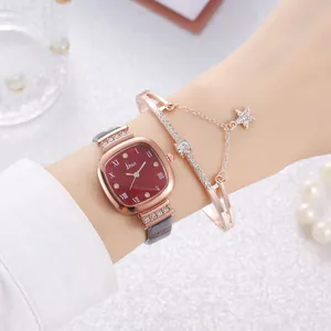 Close-up of square red dial watch with rhinestones and star charm bracelet on wrist