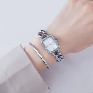 Detail of silver rectangular watch with crystal bezel and matching bangle set on wrist